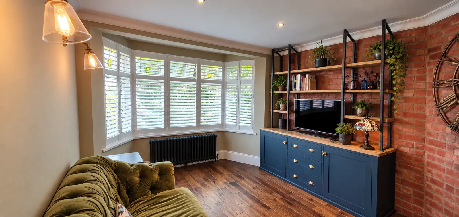 White bay-window shutters beside bookcases and a brick fireplace