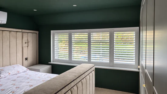 White shutters above a worktop in a green kitchen