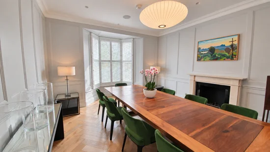 White shutters around a dining-room bay with a wooden table